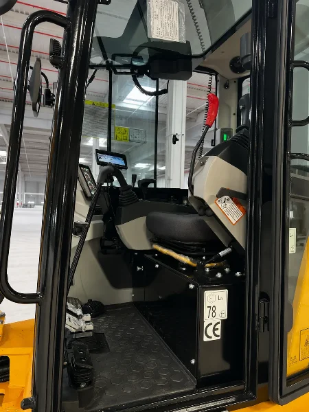 Интериор на кабината на Lonking CDM6060 с операторска седалка, стъклен вход и зона за управление.