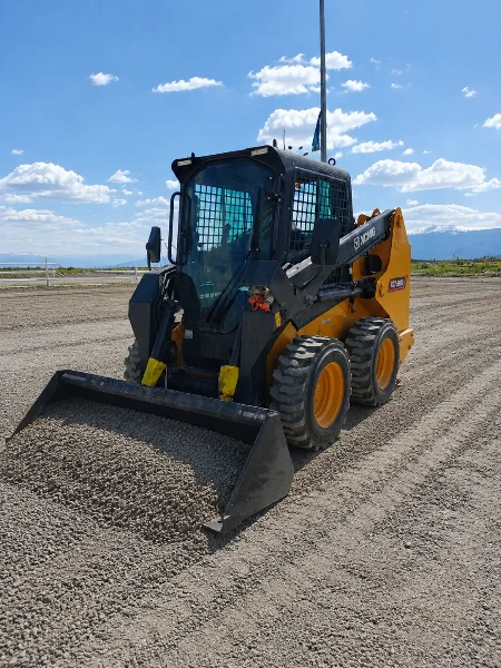 XCMG XC7-SR08 mini skid steer loader loading gravel for site preparation and material handling.