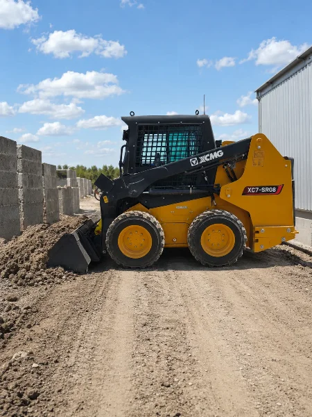 XCMG XC7-SR08 mini skid steer loader working beside soil and gravel on a compact jobsite.