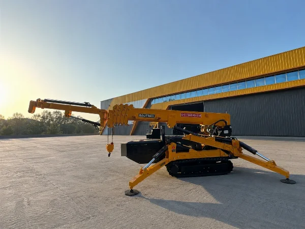 BAUTRAX SPC50 mini crawler crane set up with deployed outriggers and extended boom at an industrial site at golden hour